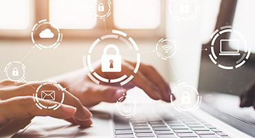 Image of hands typing on keyboard with graphic of locks, envelope, cloud, WiFi and laptop over it