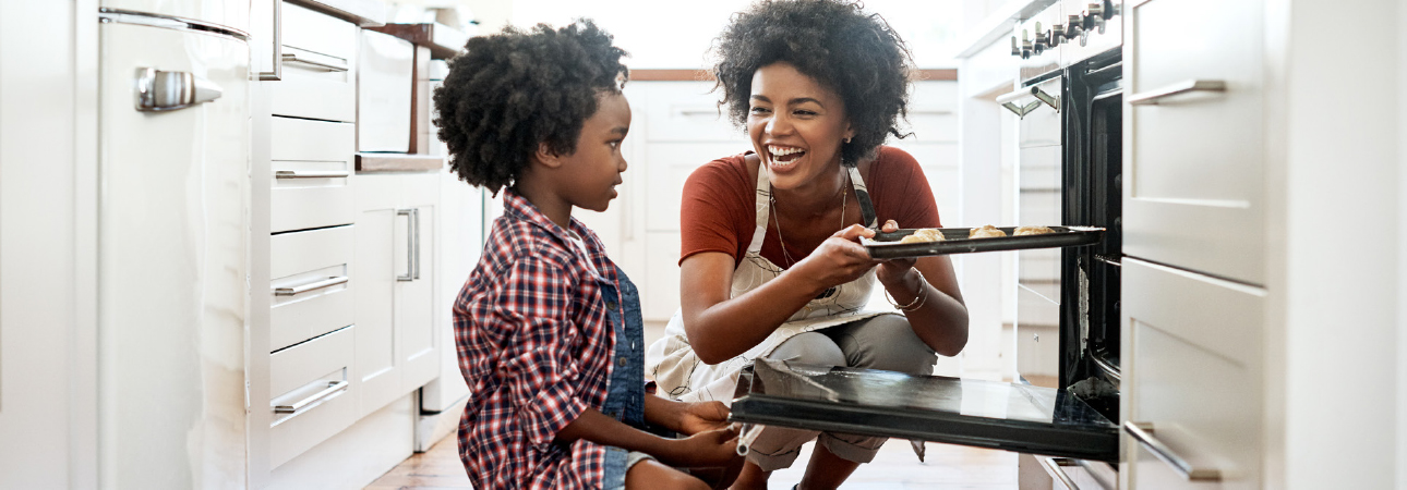 Woman and child putting cookies into oven